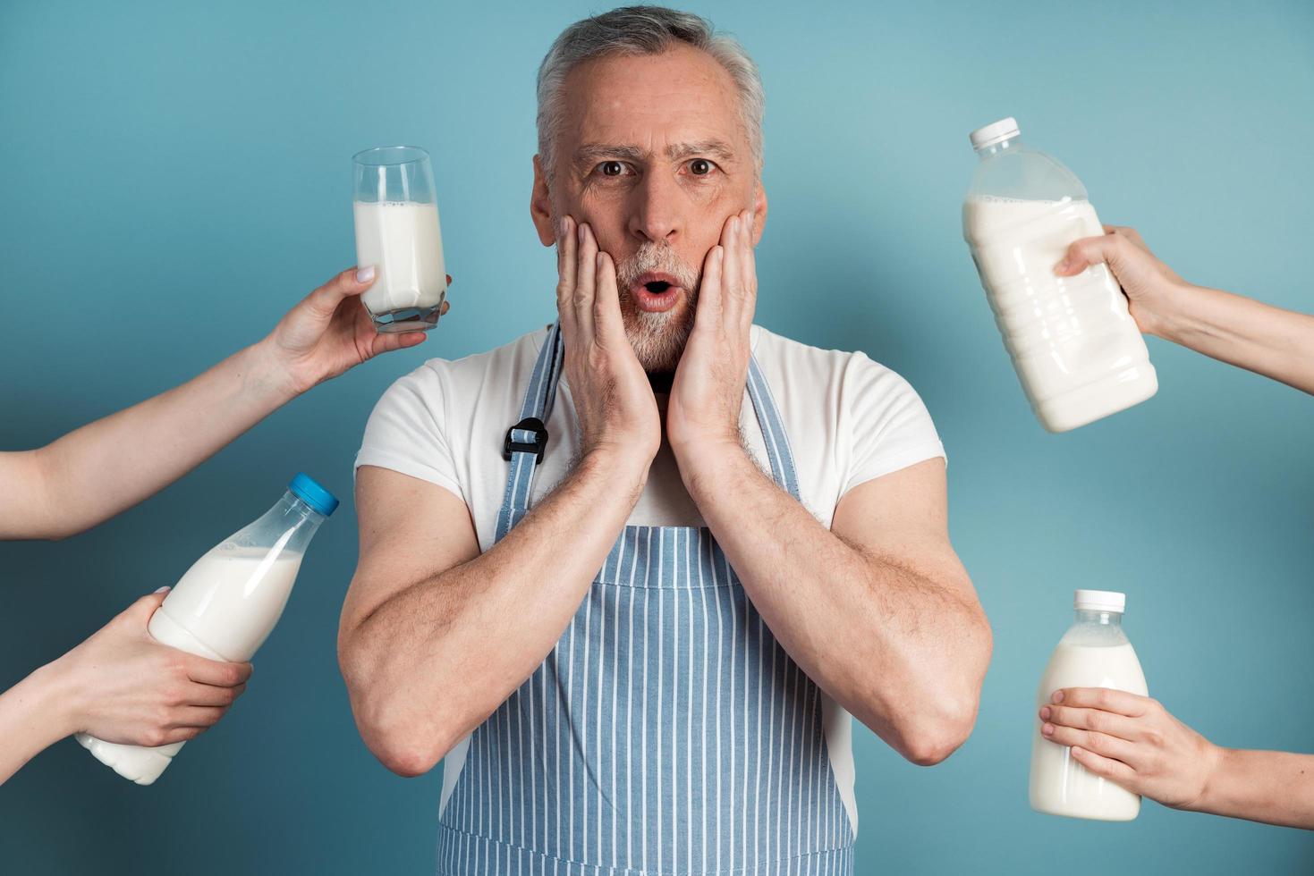 Surprised man touches his face with his hands, he wears an apron photo