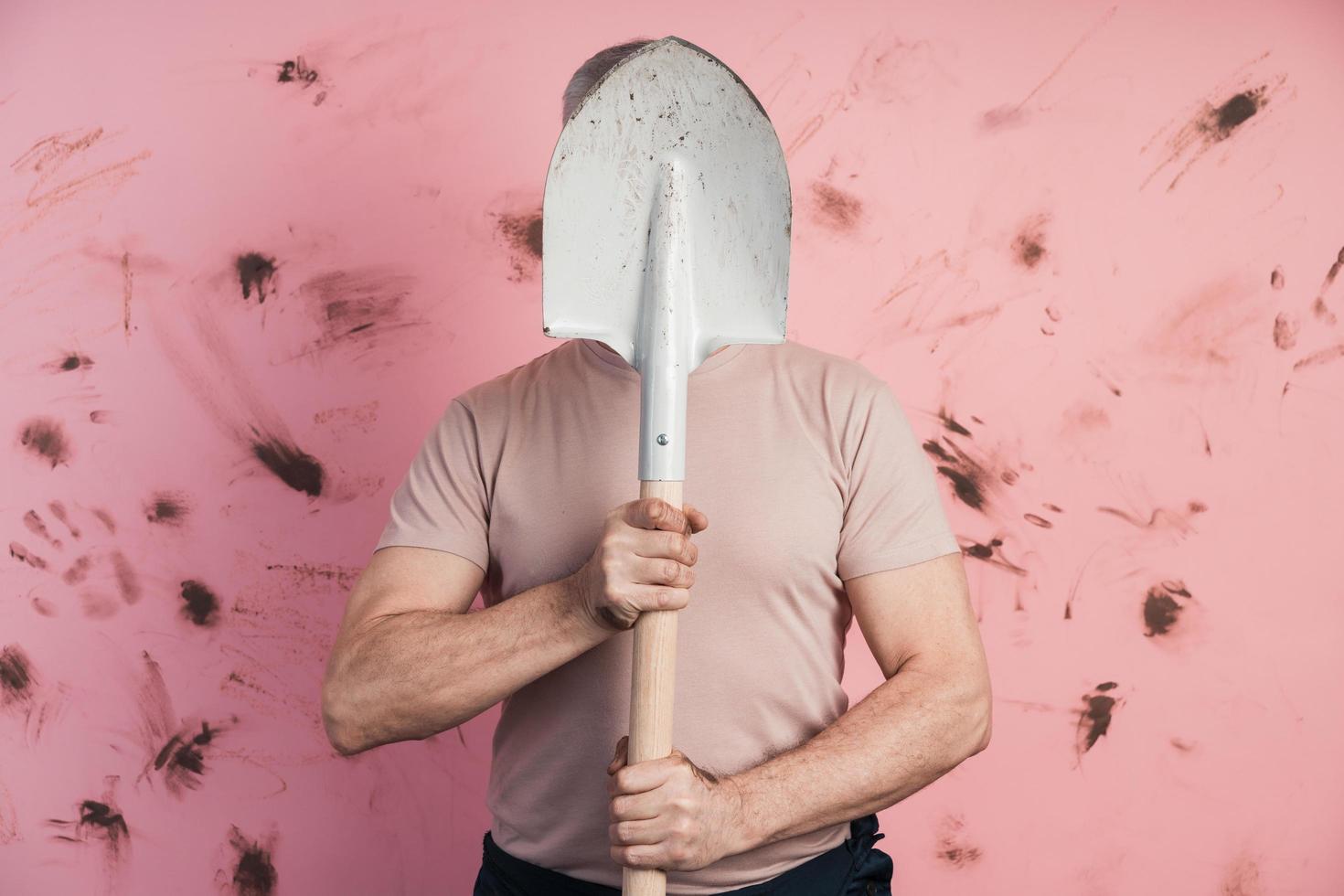 Man hid behind a shovel on a pink background photo