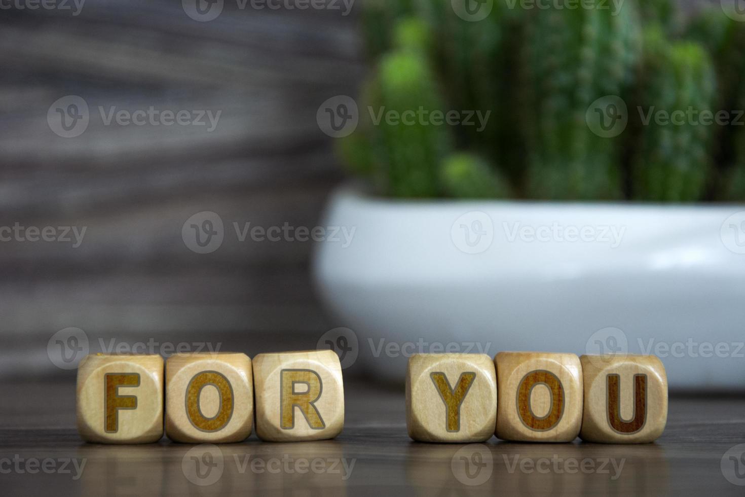 The word FOR YOU on wooden cubes on a blurred background near photo