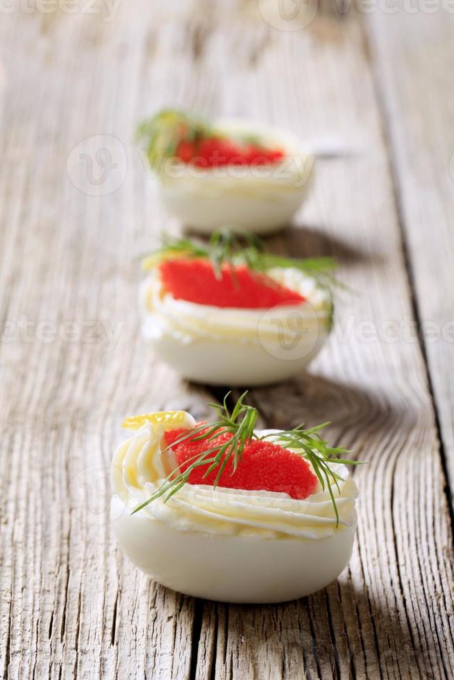 Boiled egg whites filled with red caviar photo