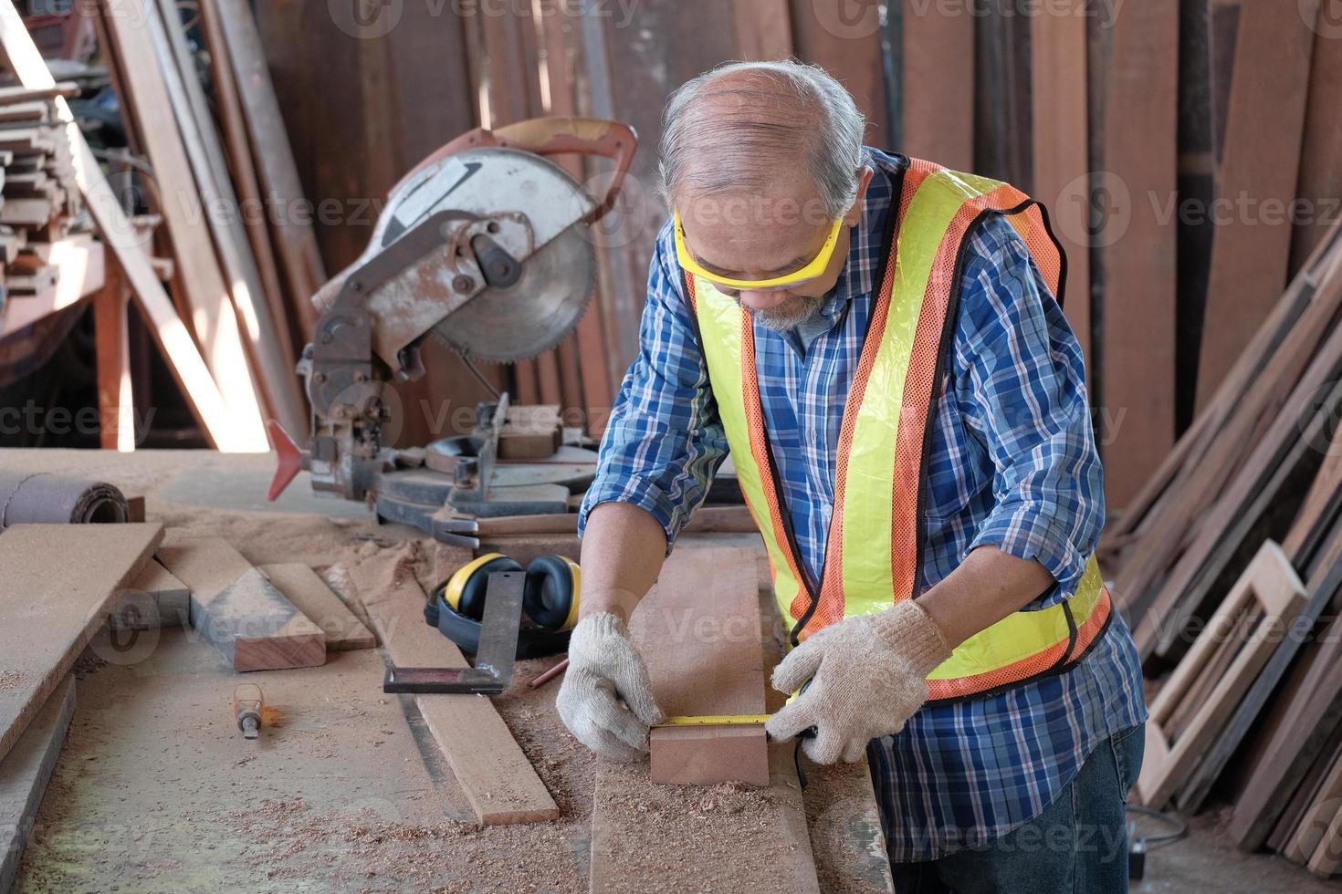 Carpintero masculino asiático senior en la fábrica de madera. foto