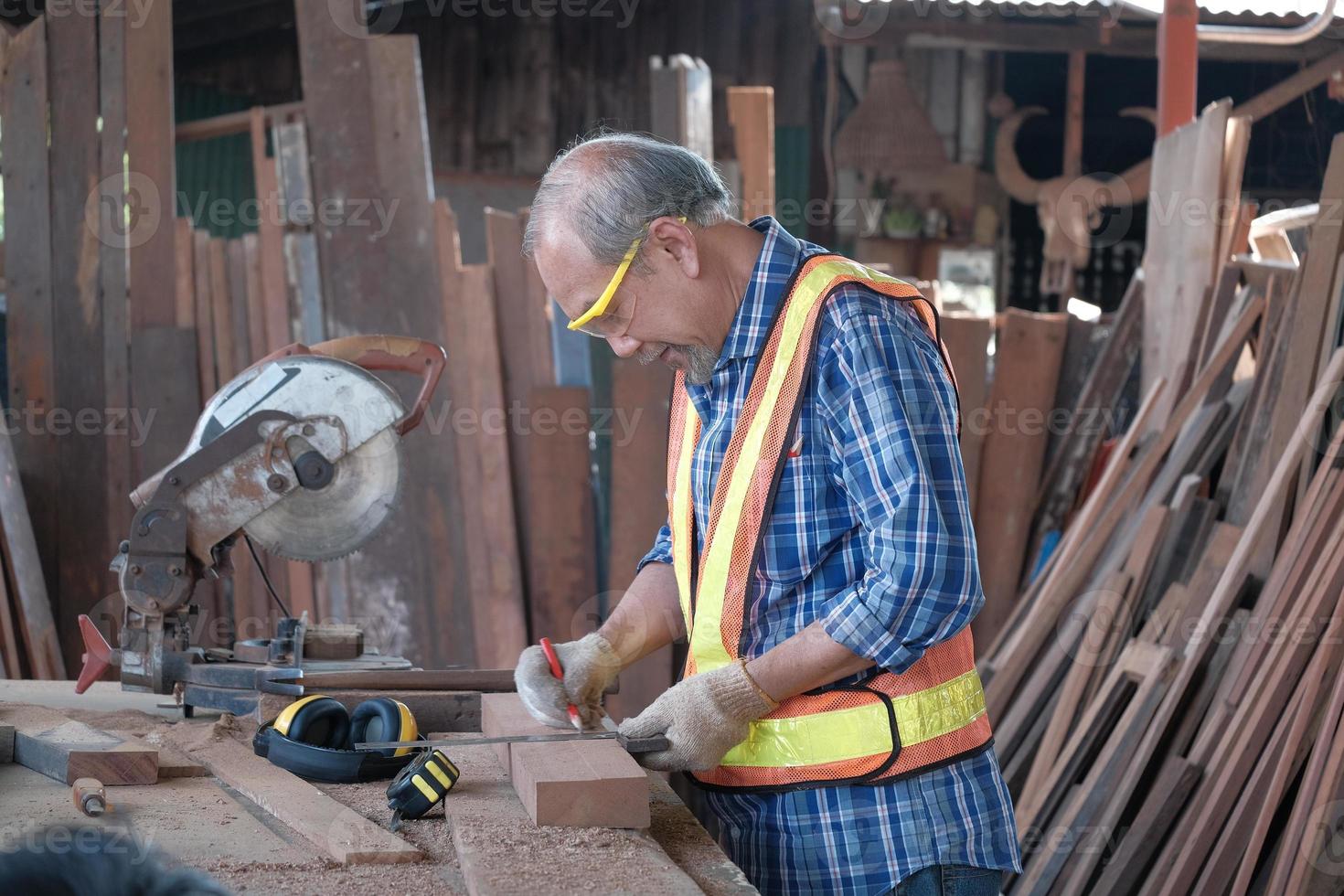 Senior male carpenter works in the timber factory. photo