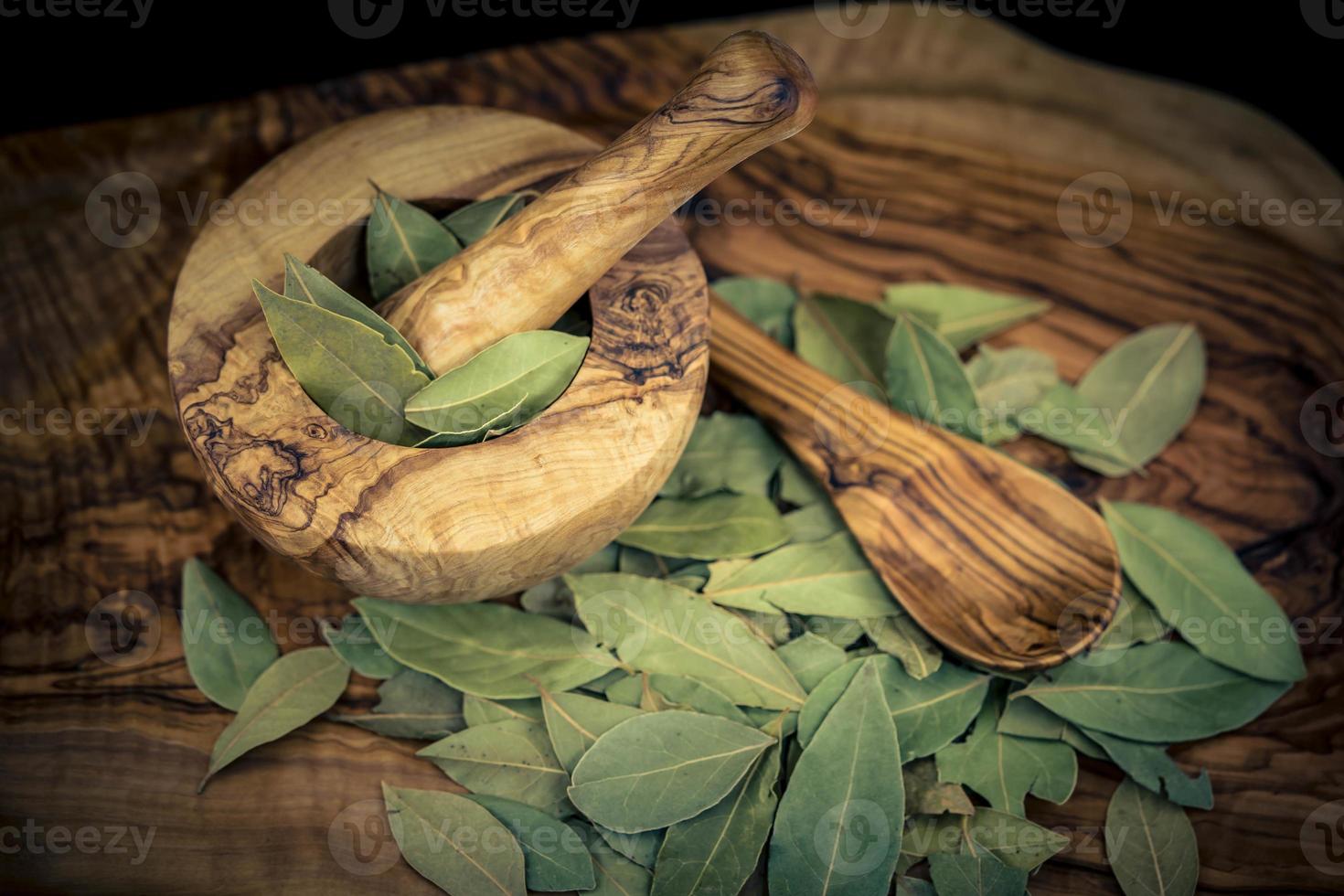 hojas de laurel y bayas de enebro en madera de olivo foto