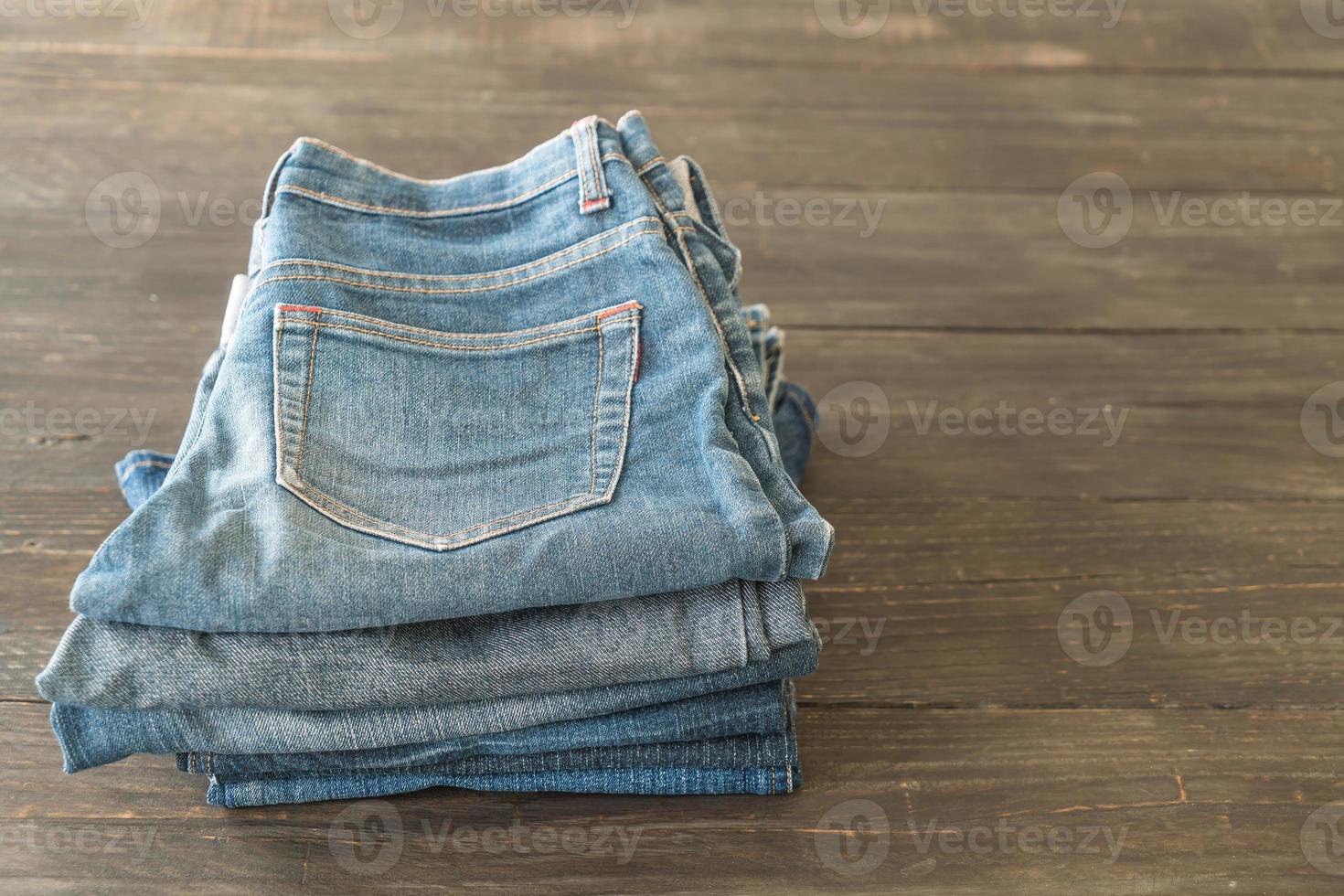 Stacks of jeans clothing on wood background photo