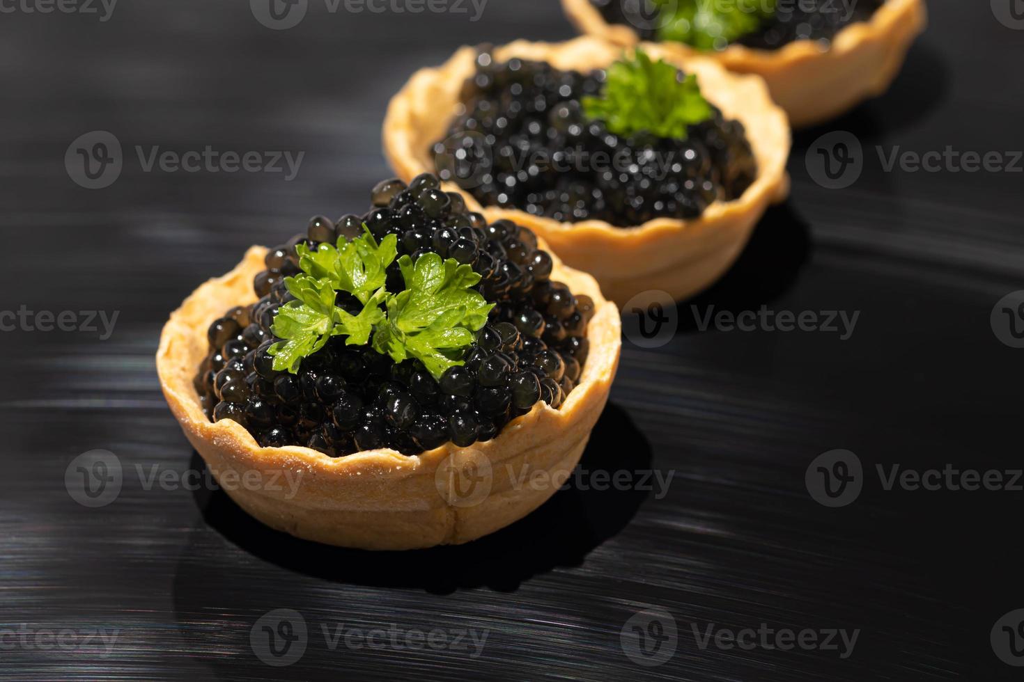 caviar negro en tartaletas sobre un fondo oscuro. concepto de comida sana. foto