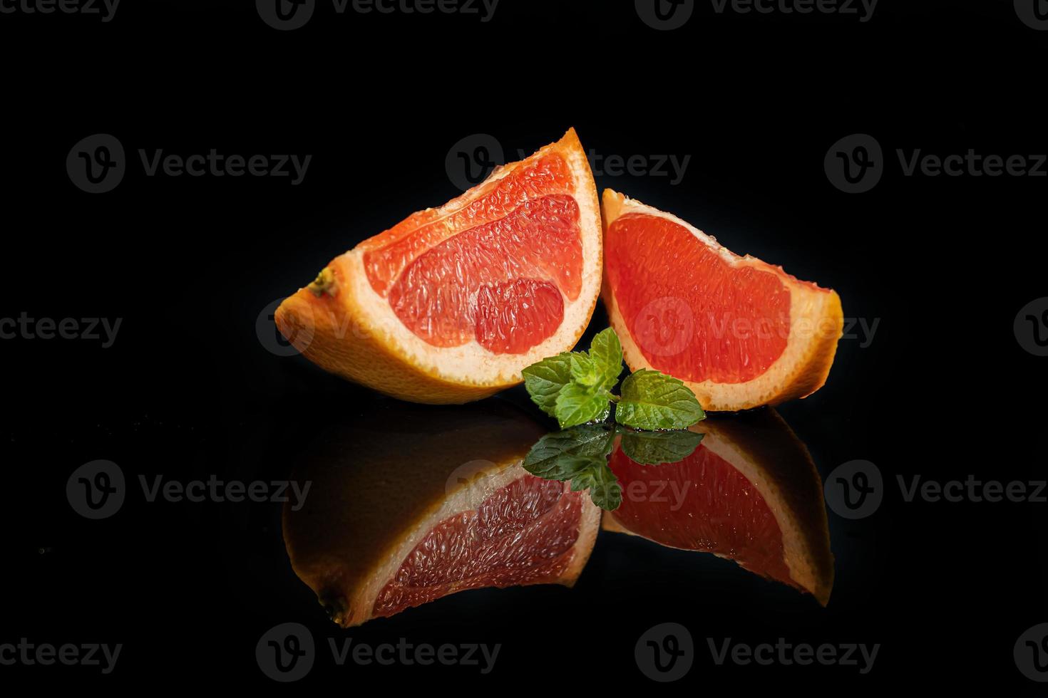 rodajas de pomelo sobre un fondo oscuro con una ramita de menta. foto