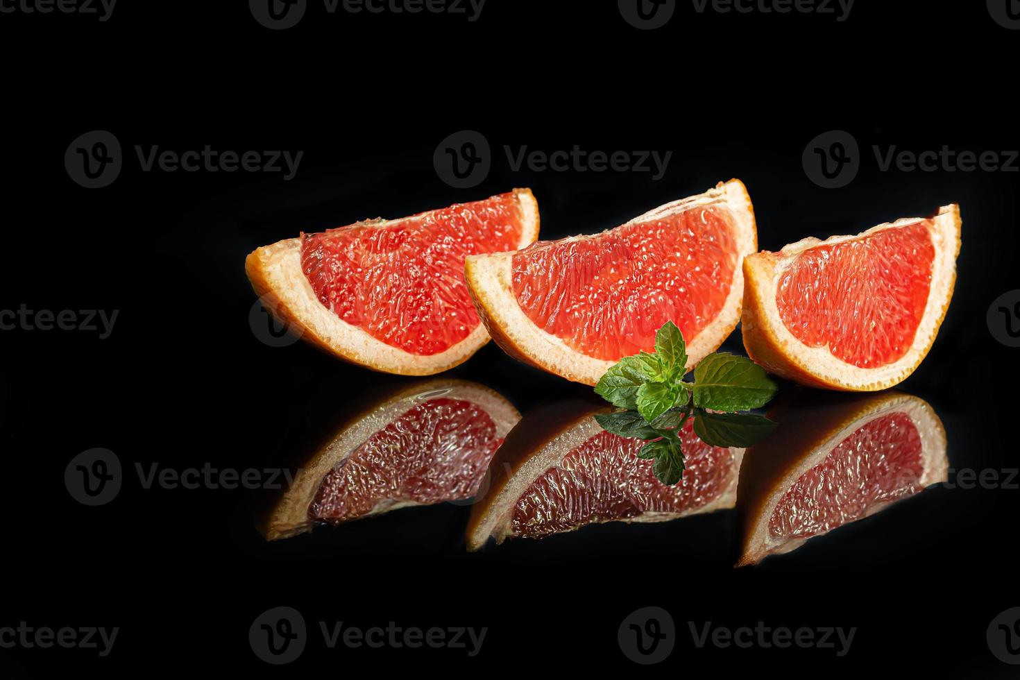 Slices of grapefruit on a dark background with a sprig of mint. photo