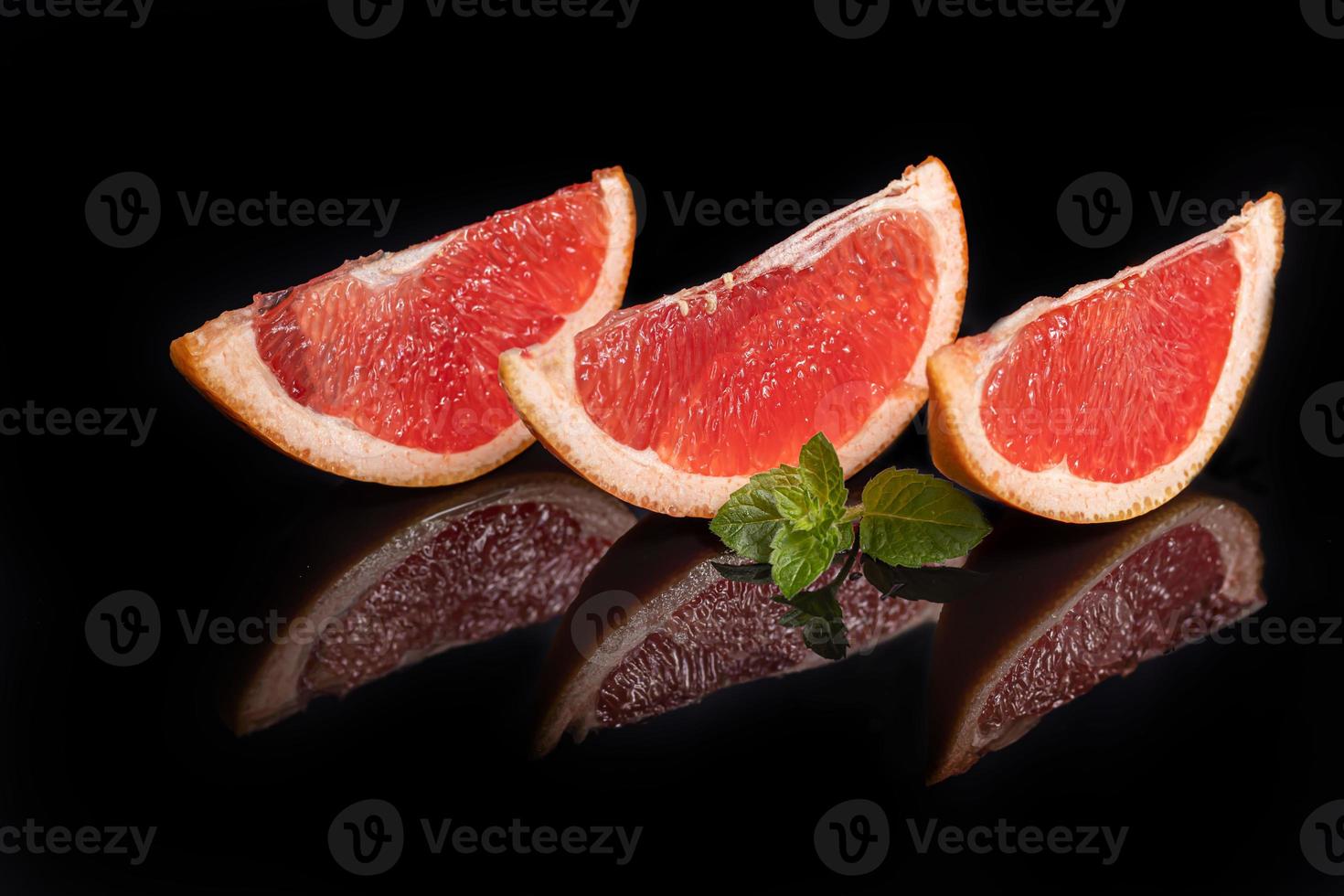 Slices of grapefruit on a dark background with a sprig of mint. photo