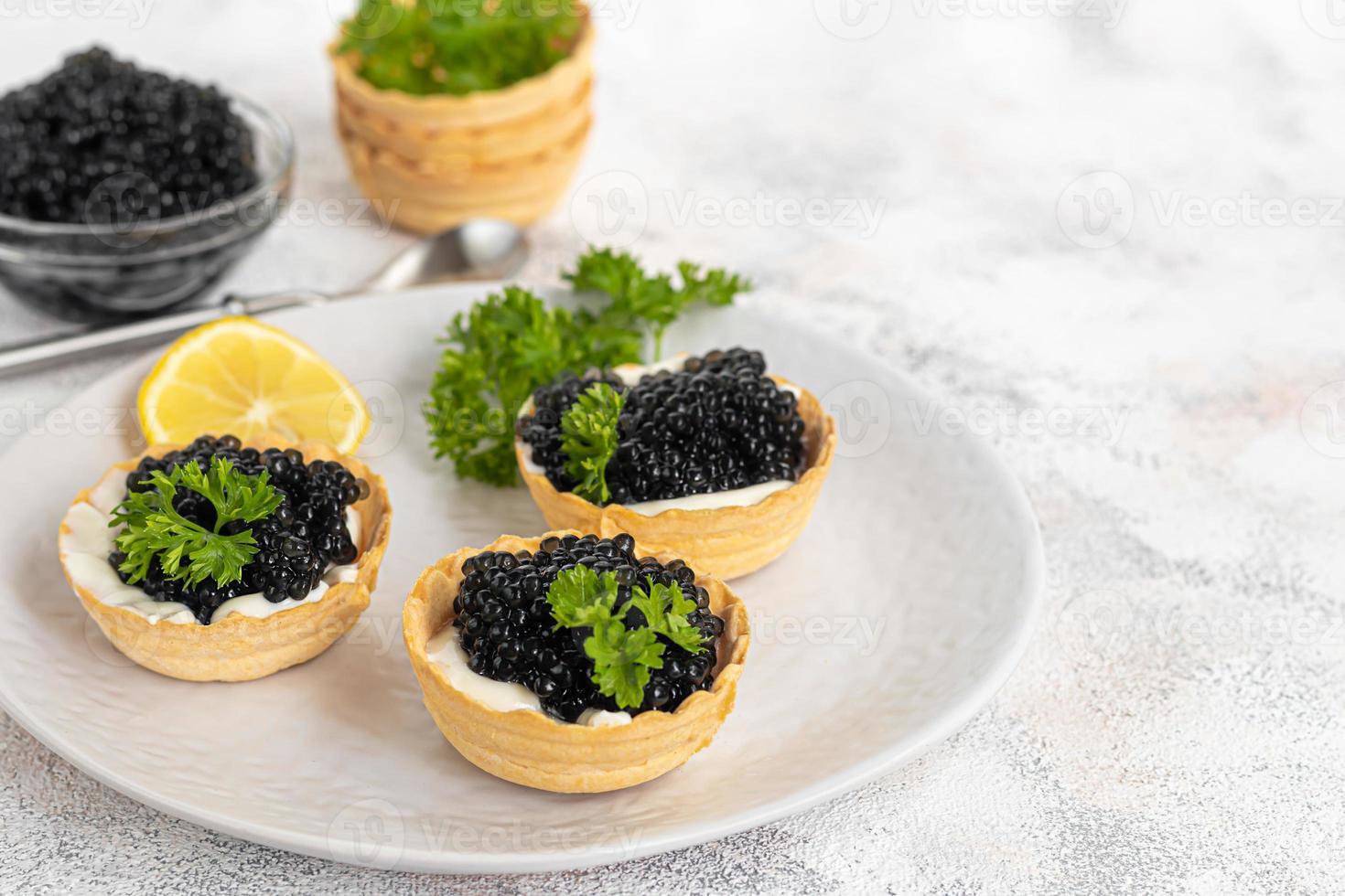 Black caviar in tartlets on a light background. Healthy food concept. photo