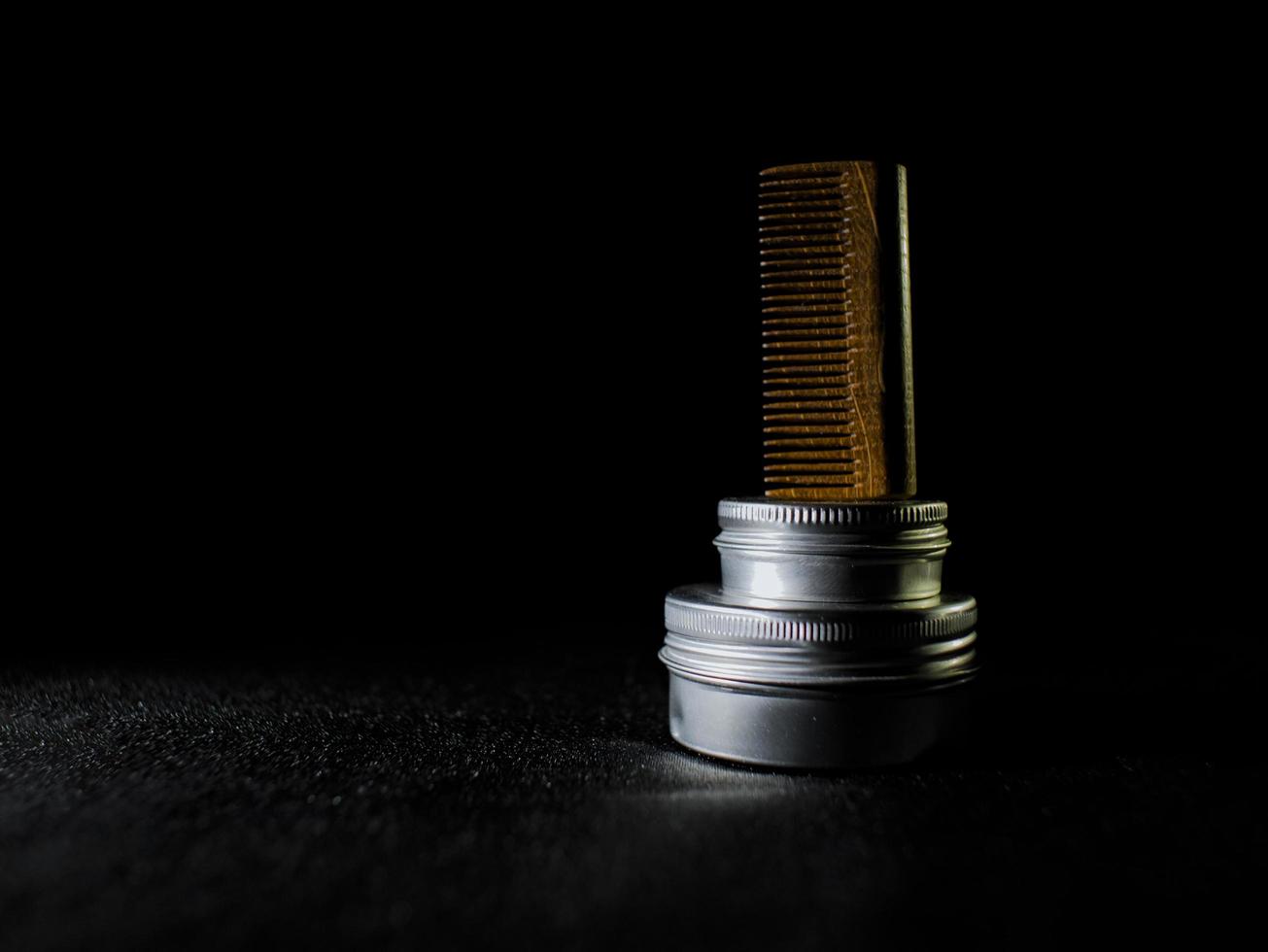 Wooden comb and jars of beard and mustache wax on a black background photo