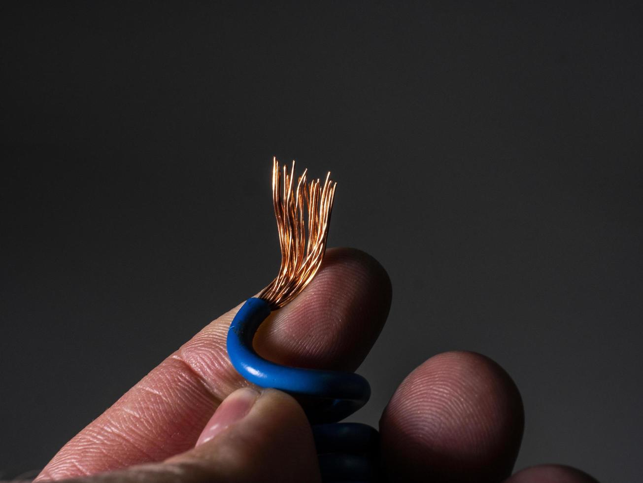 Cable azul desnudo al final de cerca en la mano de un hombre foto