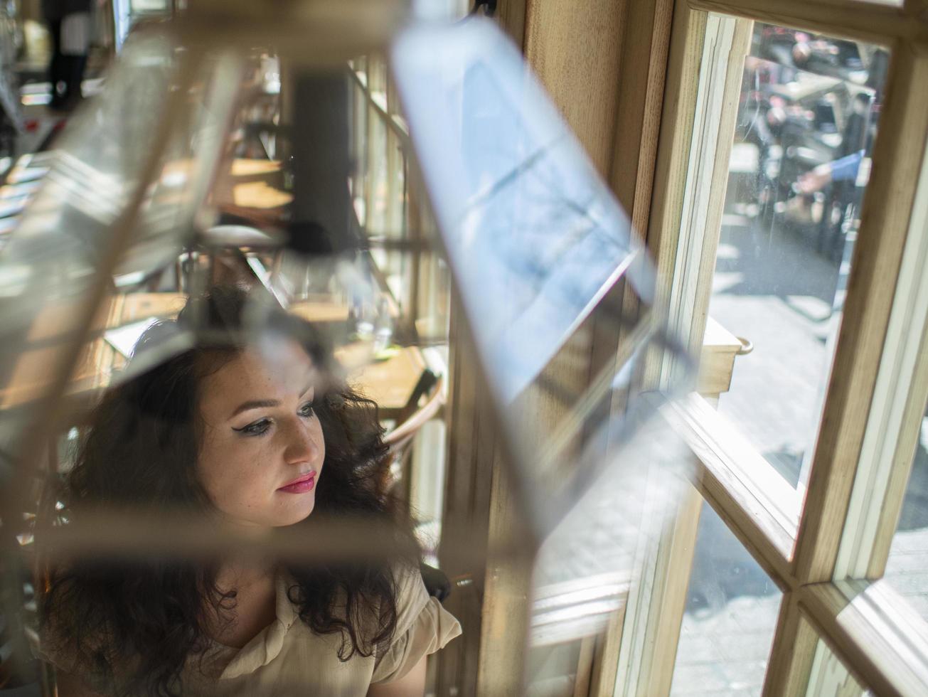 linda chica con el pelo rizado se sienta en una mesa en un café foto