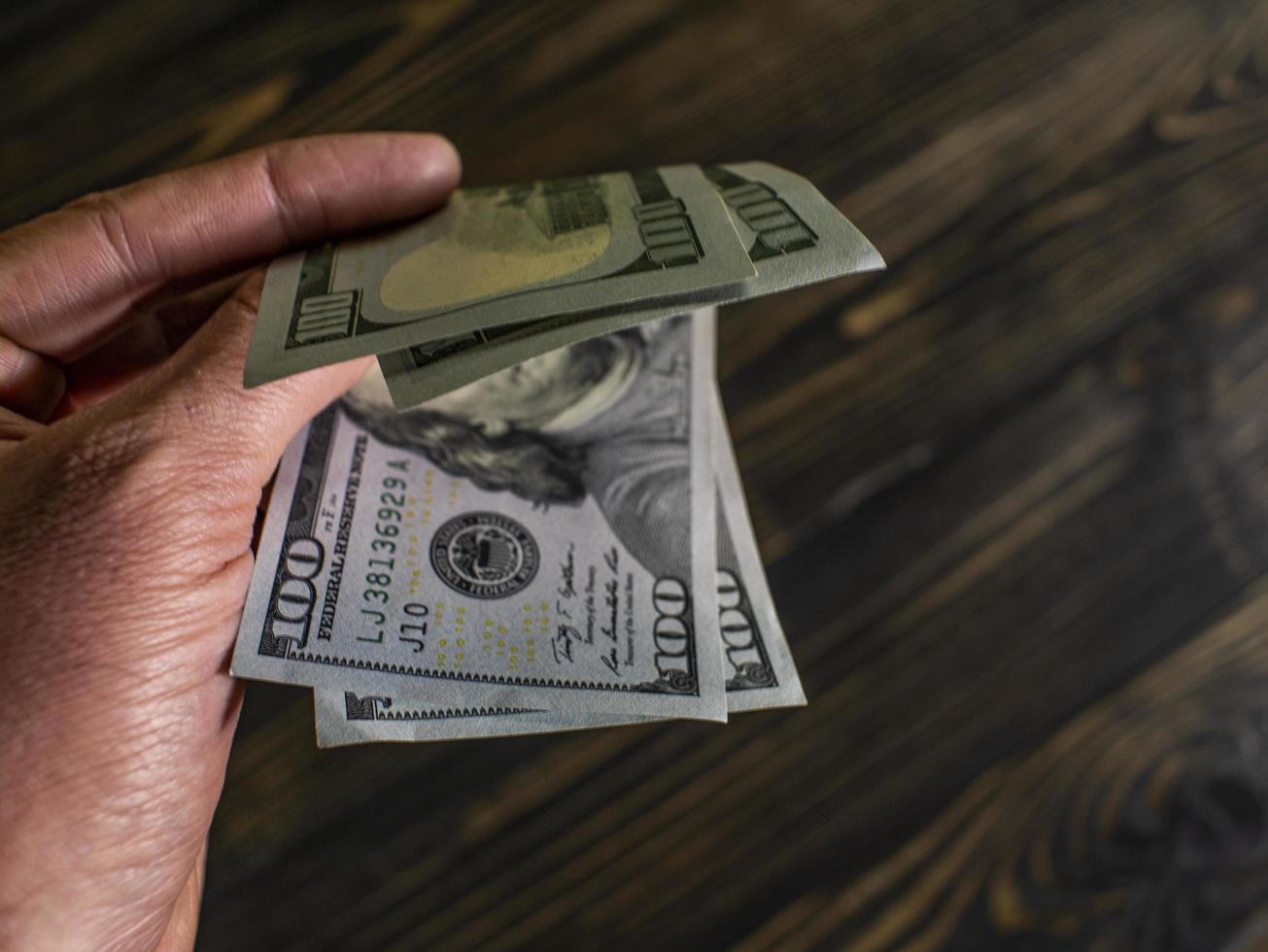 Close up of male hand holds two banknotes of hundred dollars photo