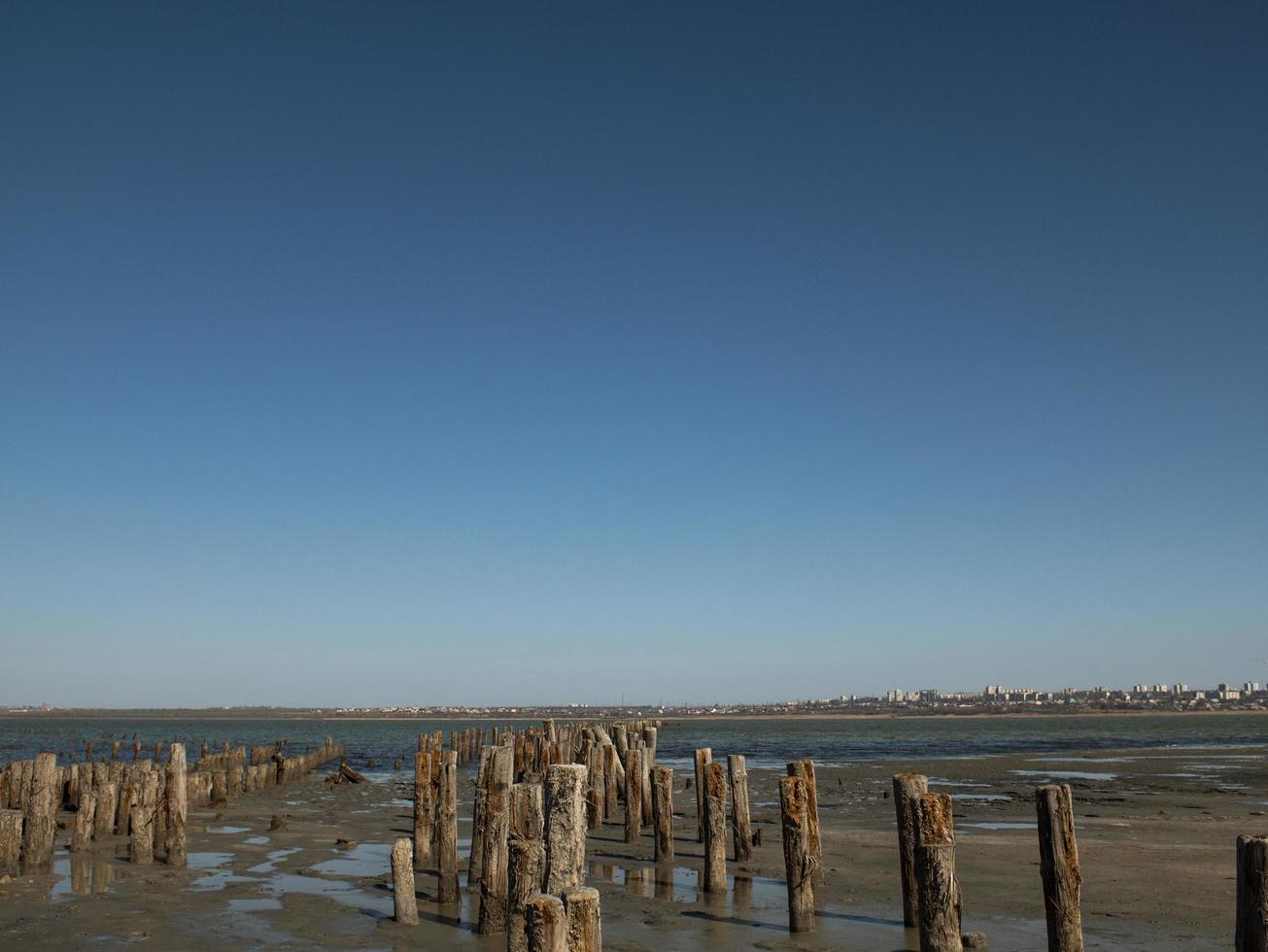 Bolardos de madera en la arena contra la ría foto