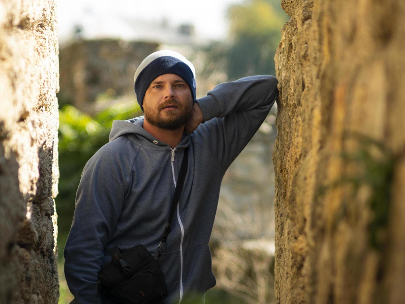 Hombre con gorro de punto y chaqueta con capucha posando en un barranco foto