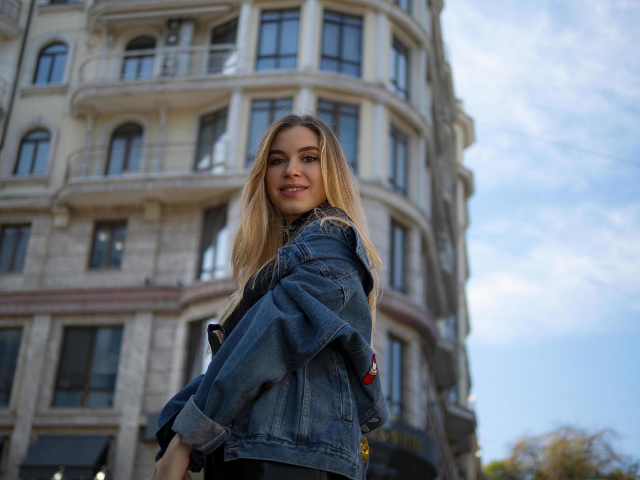 Atractiva chica rubia sonriendo en el fondo de un edificio moderno foto