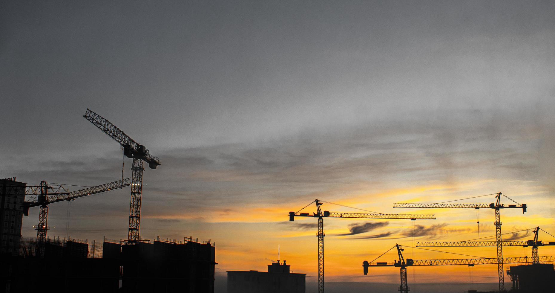 construcción de edificios con grúas durante la puesta de sol. construcción de grúas foto
