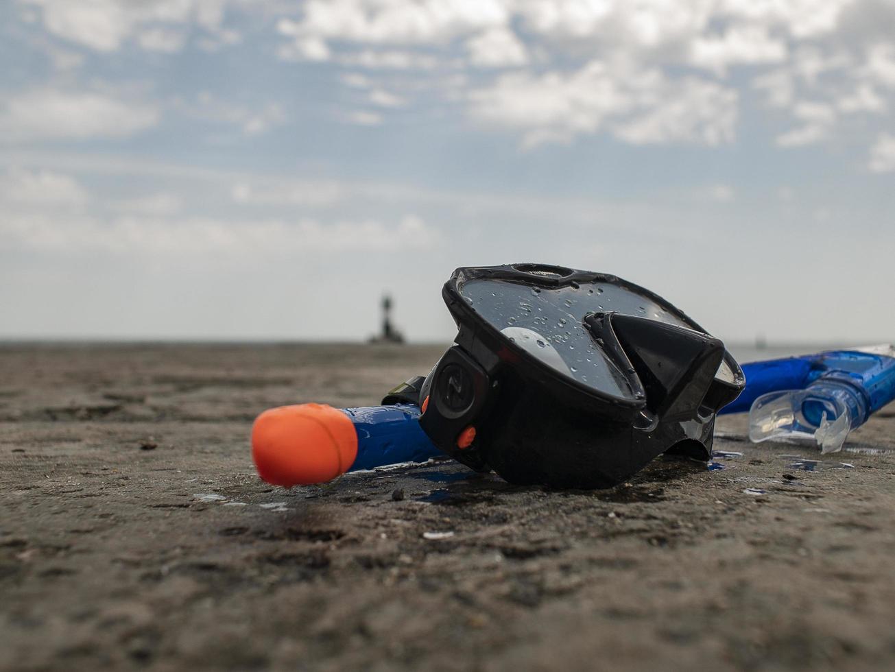 black diving mask and snorkel on a concrete pier photo