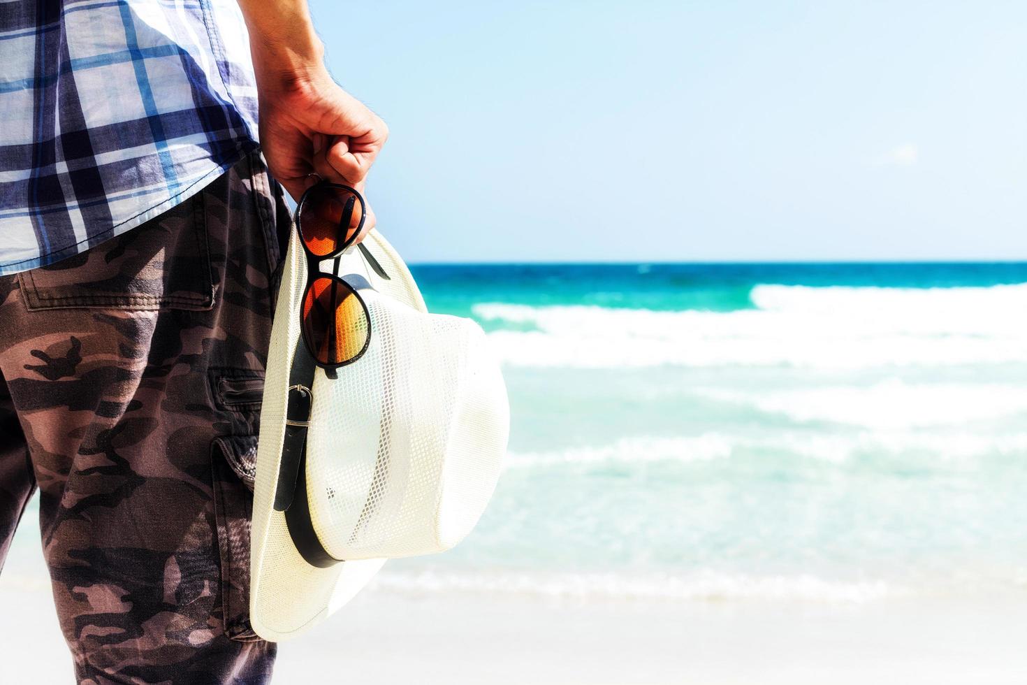 Cerrar turista sosteniendo sombrero de paja y gafas de sol foto