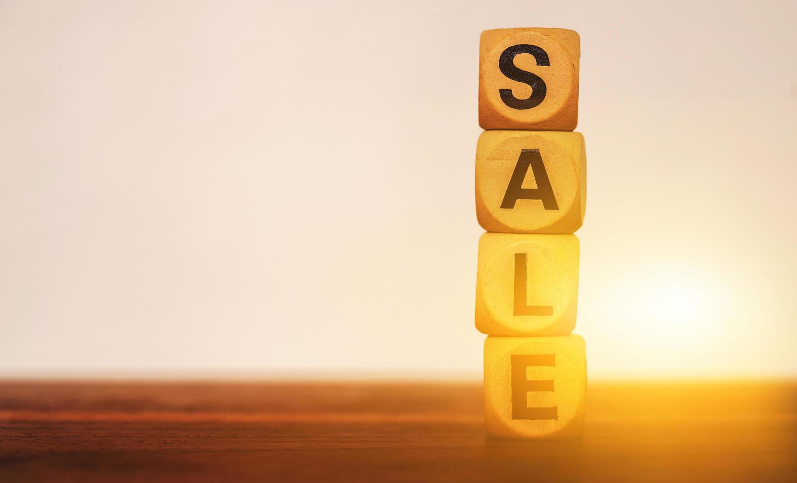 Sale concept with wooden block on wooden table at sunset background photo