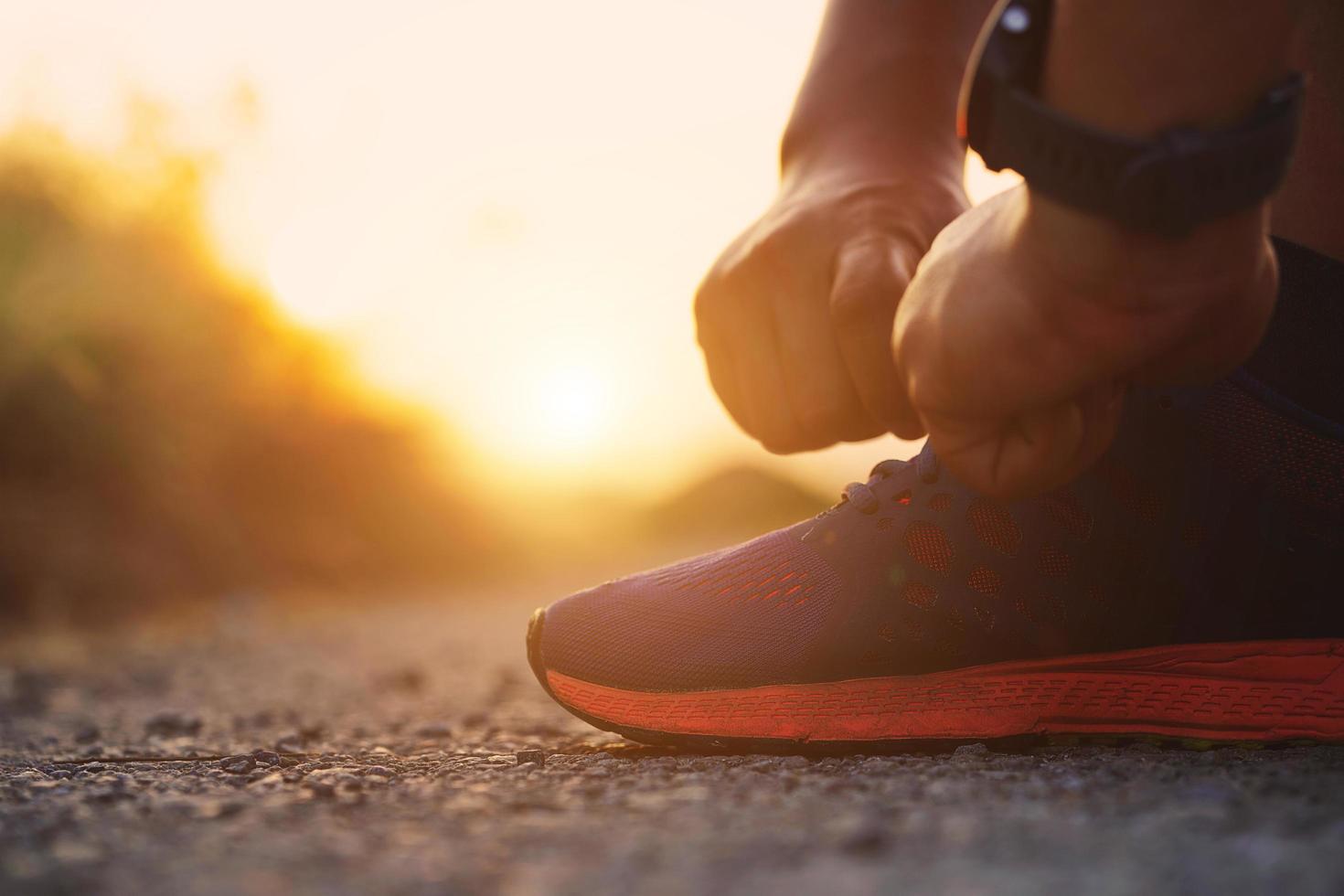 Deportista atar zapatillas con fondo puesta de sol. foto