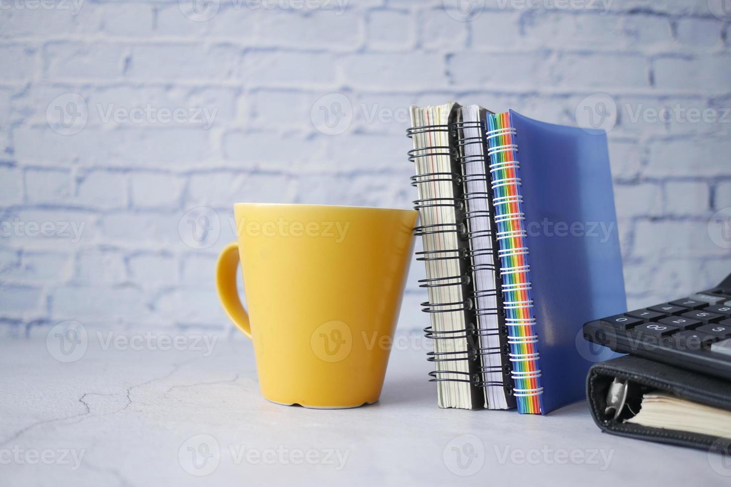 yellow color mug mockup with with notebooks on table photo