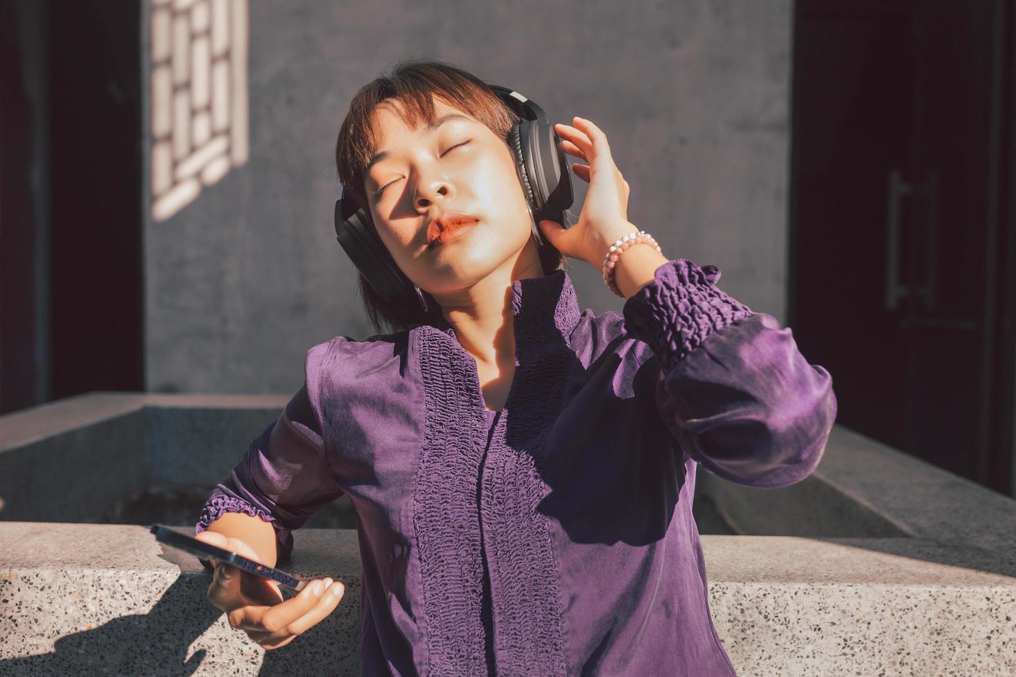 Feliz joven mujer asiática escuchando música con auriculares foto