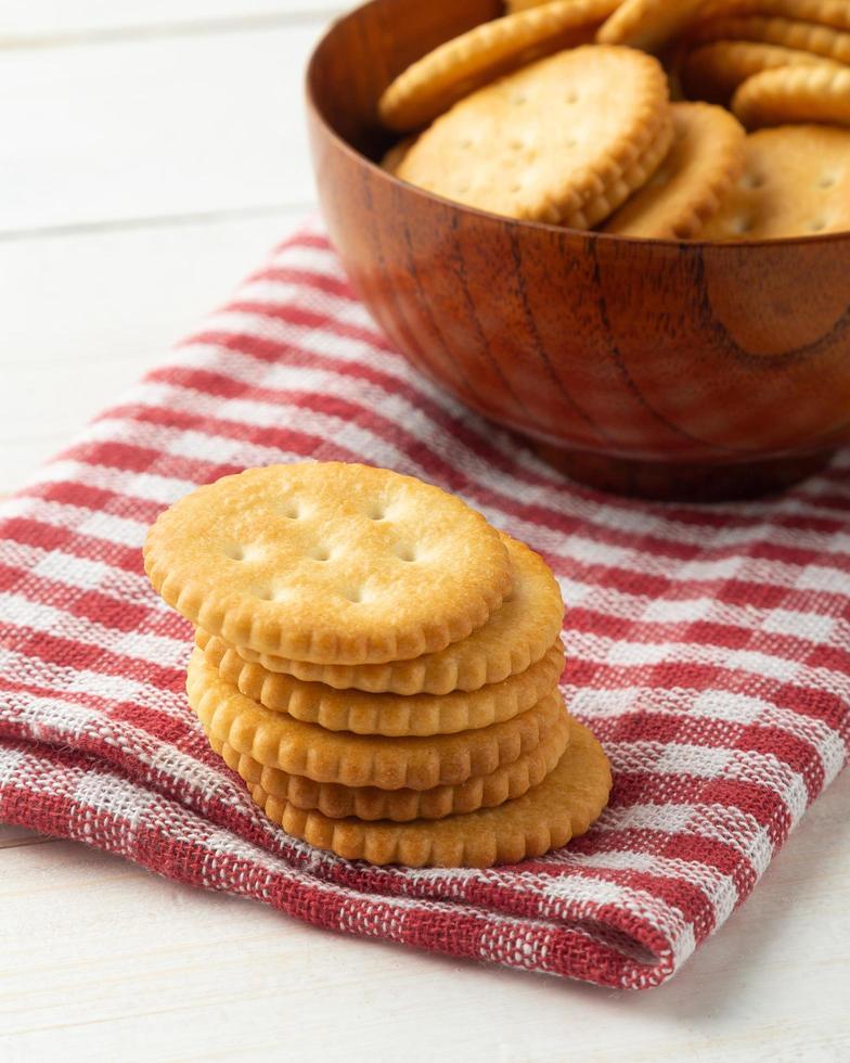 Galletas cracker redondeadas en un cuenco de madera con mantel foto