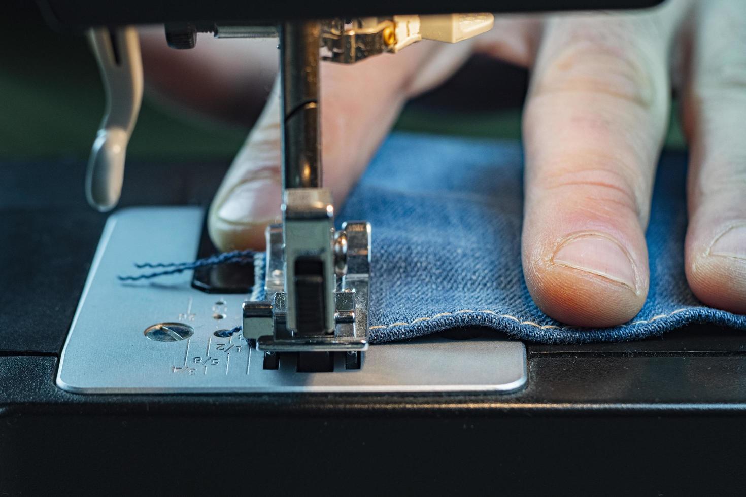 Primer plano de mezclilla de coser a mano masculina en una máquina de coser foto