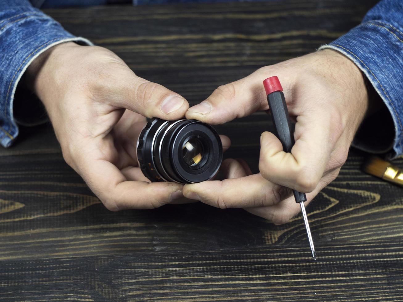 male holding old manual lens and screwdriver photo