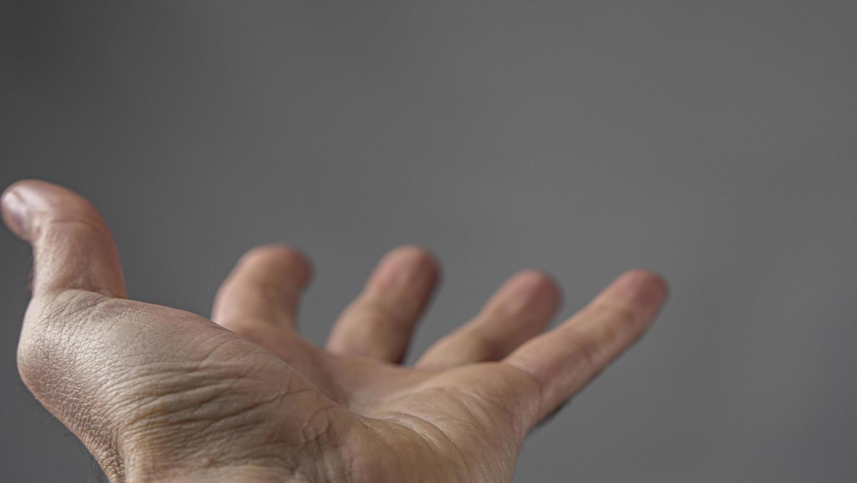 Man's Hand Begs For Something On A Gray Background photo