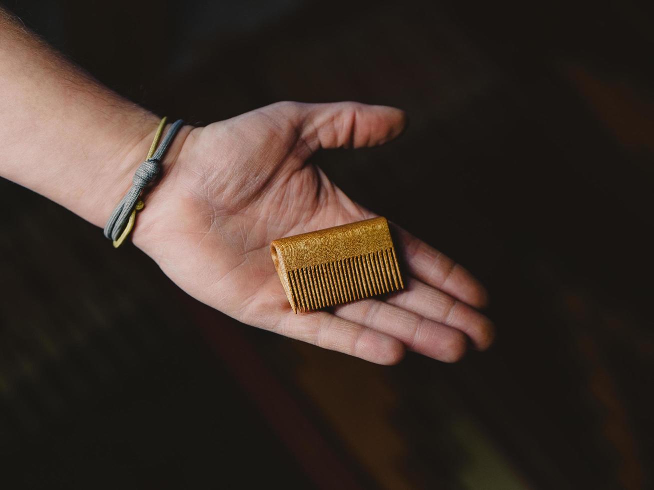 a man holding a handmade beard comb in his hand photo