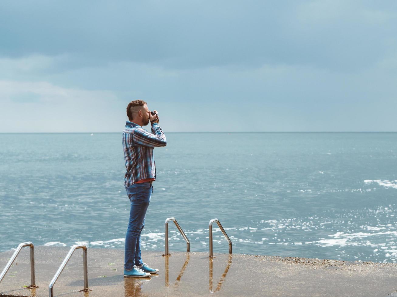 Fotógrafo profesional con una cámara hace una foto del mar.