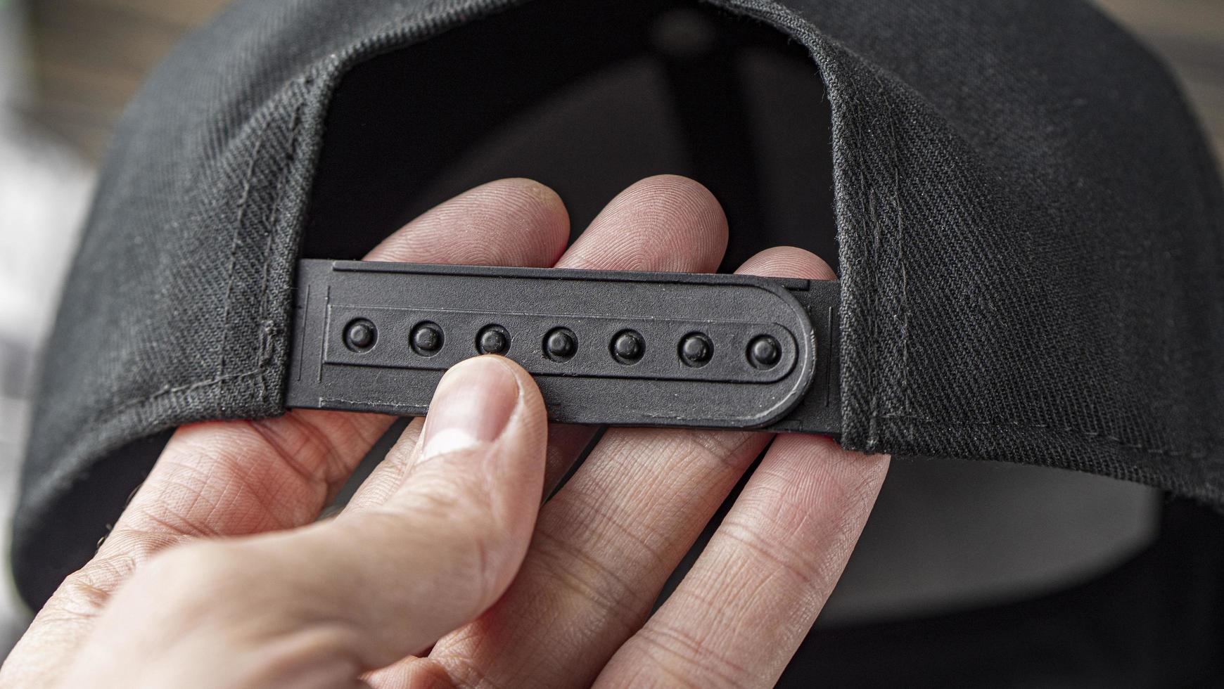 Fragment Of A Plastic Black Clasp Of A Baseball Cap In A Male Hand photo