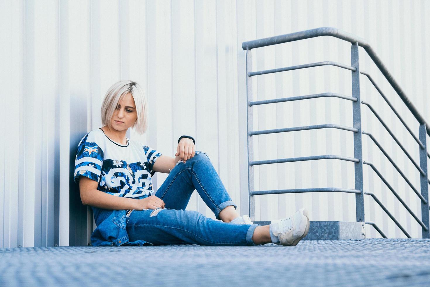 Hermosa chica con el pelo corto y blanco vestida con jeans en estilo urbano foto