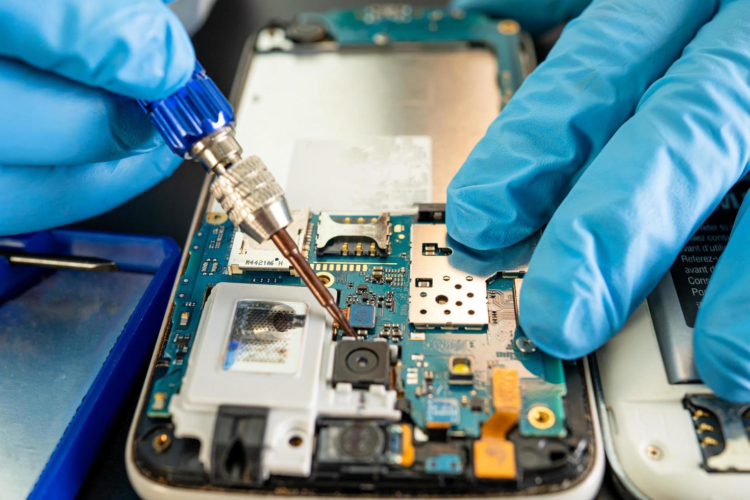 Technician repairing inside of mobile phone by soldering iron. photo