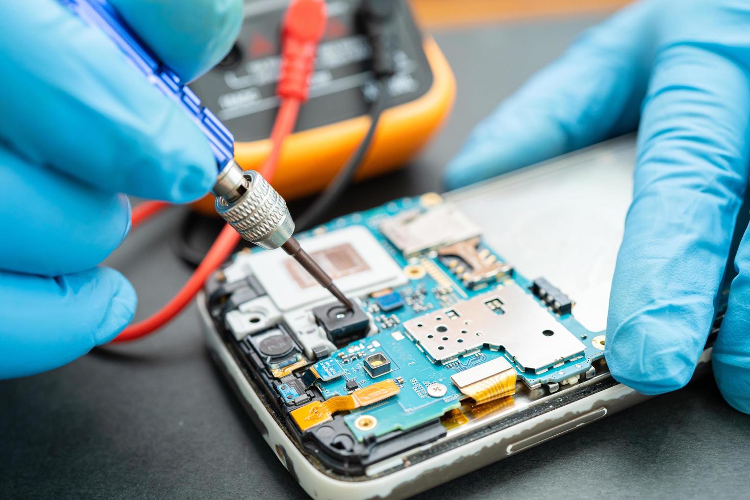 Technician repairing inside of mobile phone by soldering iron. photo