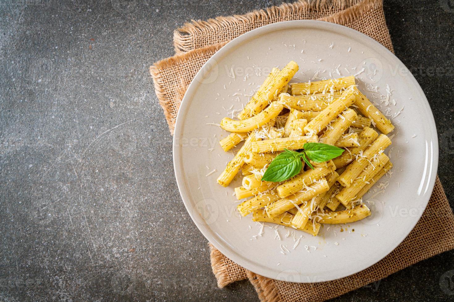 pasta al pesto rigatoni con queso parmesano - comida italiana y estilo vegetariano foto