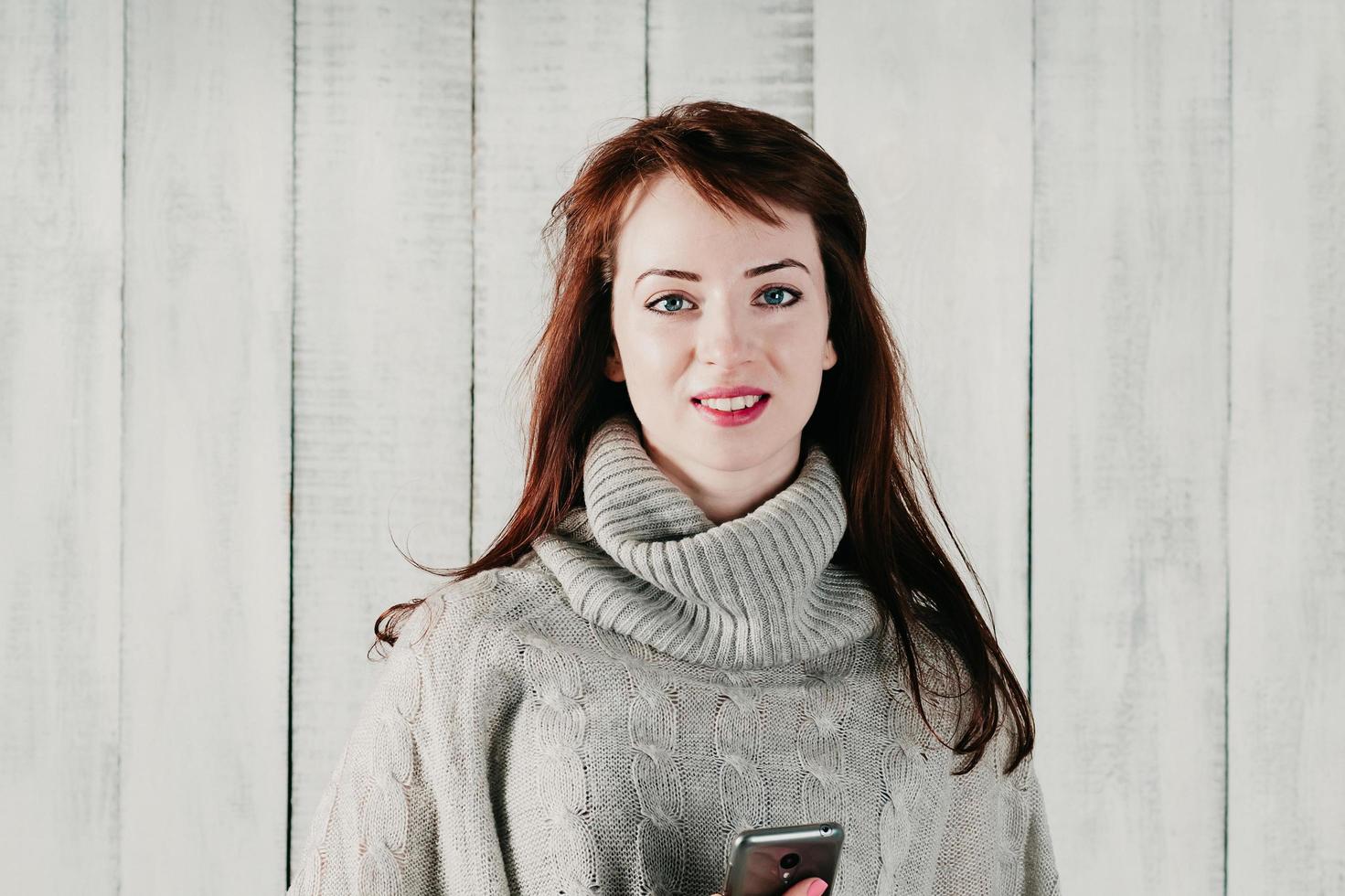 A beautiful brunette girl holding a cellphone, happily smiling photo