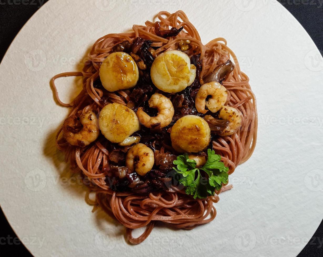 vieiras con pasta de linguini rojo, hierbas y especias foto