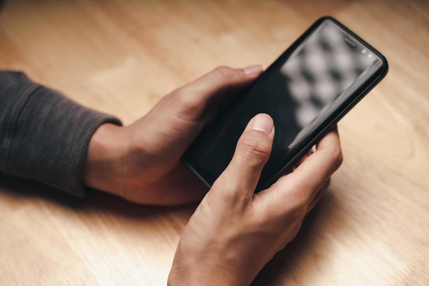 hombre que usa el teléfono inteligente en la mesa de madera, buscando, navegando, social foto