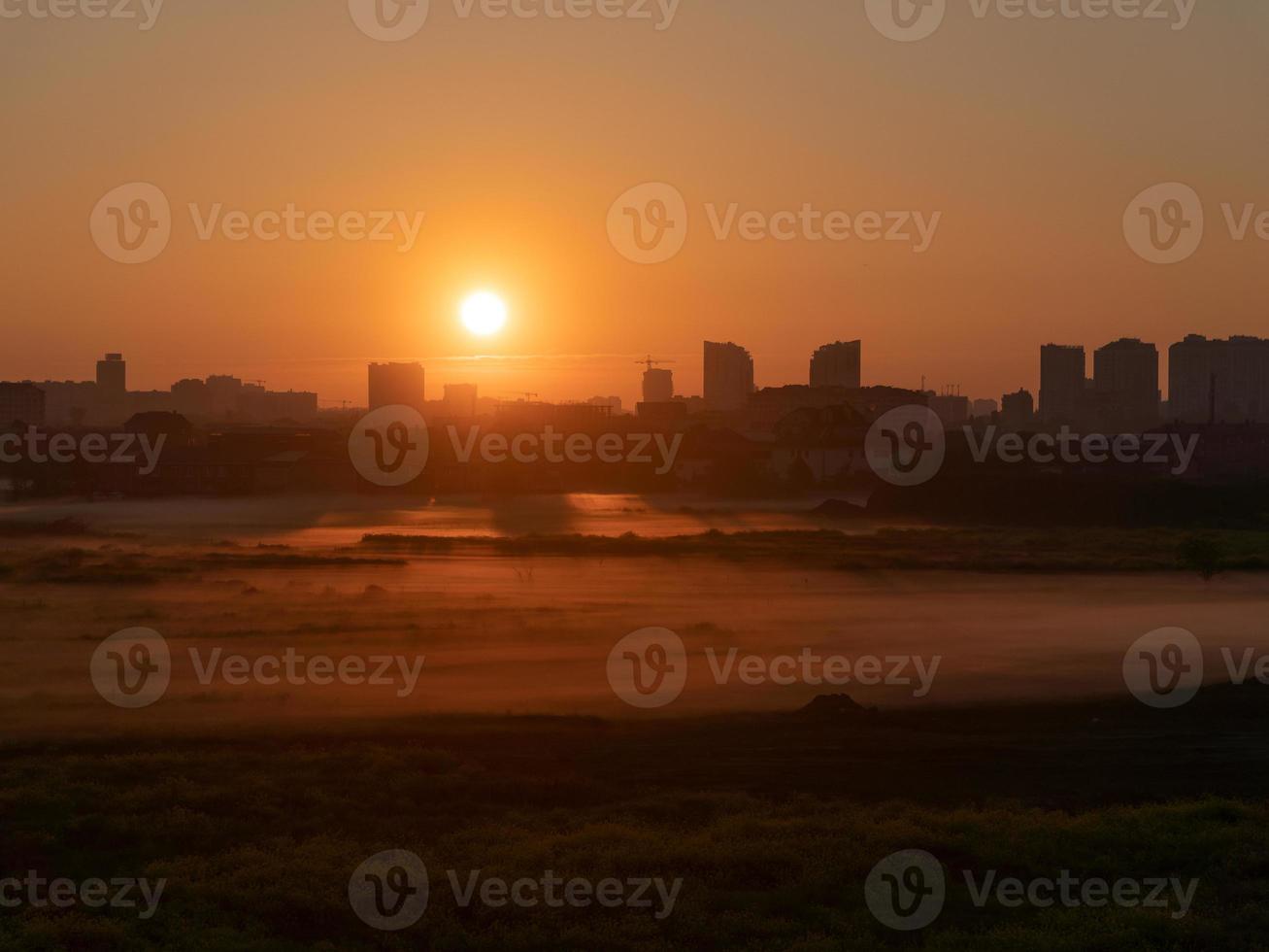 The dawn with the yellow fog on the field, with the city backdrop photo
