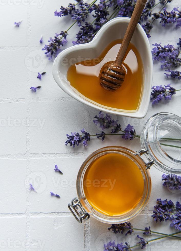 Tarro y cuenco con miel y flores frescas de lavanda. foto