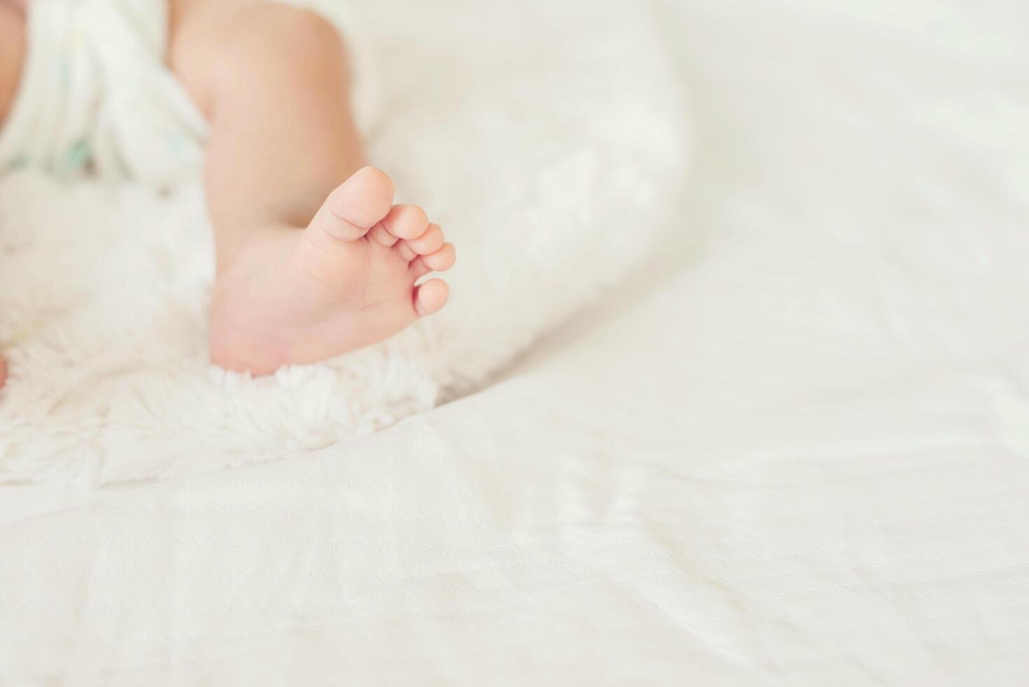 Newborn Baby legs on white bed. photo