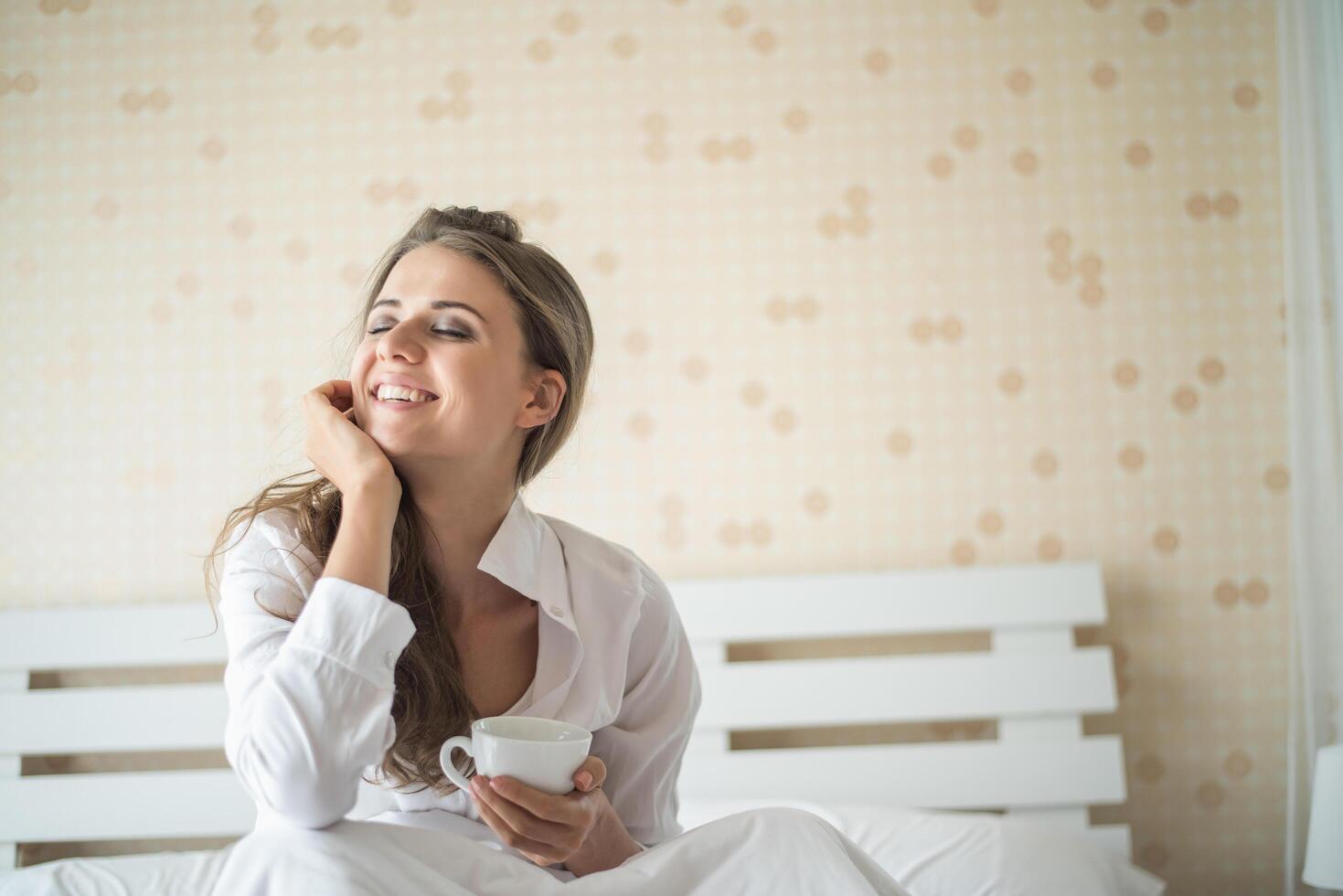 Beautiful woman at her bedroom drinking coffee in the morning photo