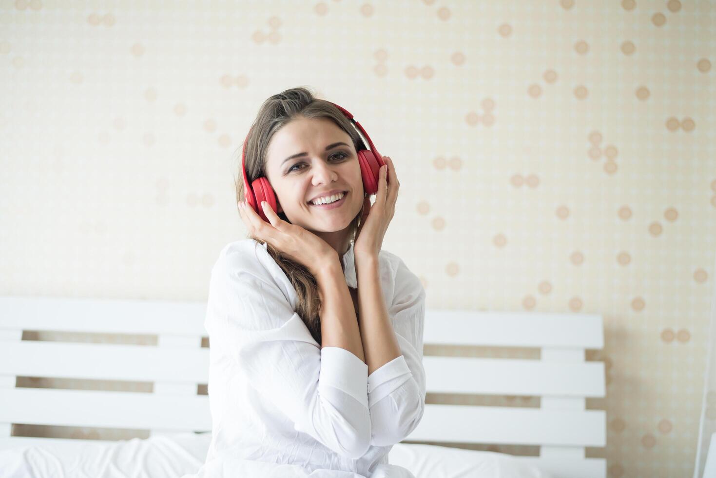 Hermosa mujer escuchando música en la mañana sentada en la cama en casa foto