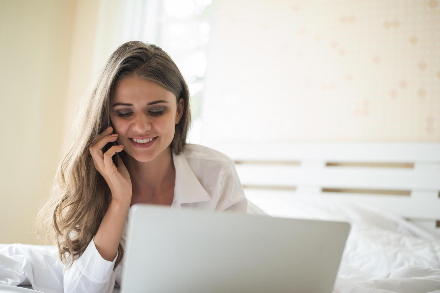 Feliz hermosa mujer trabajando en un portátil en la cama de la casa foto