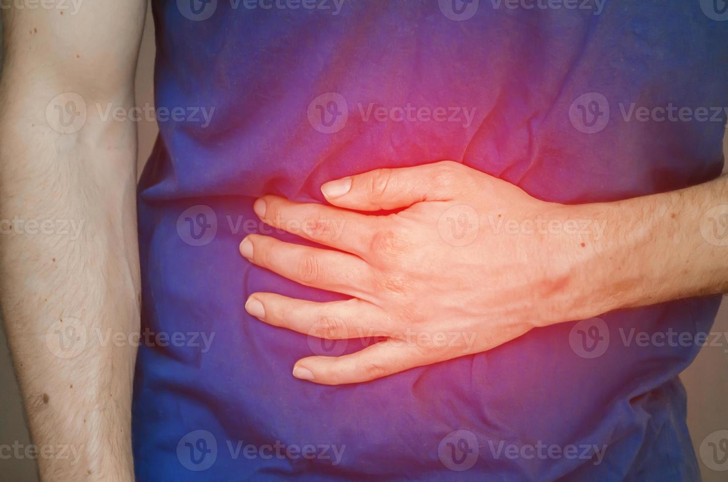 A man holding his stomach. Close up. photo