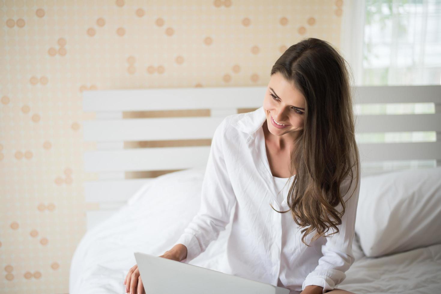 Happy Beautiful woman working on a laptop on the bed in the house photo