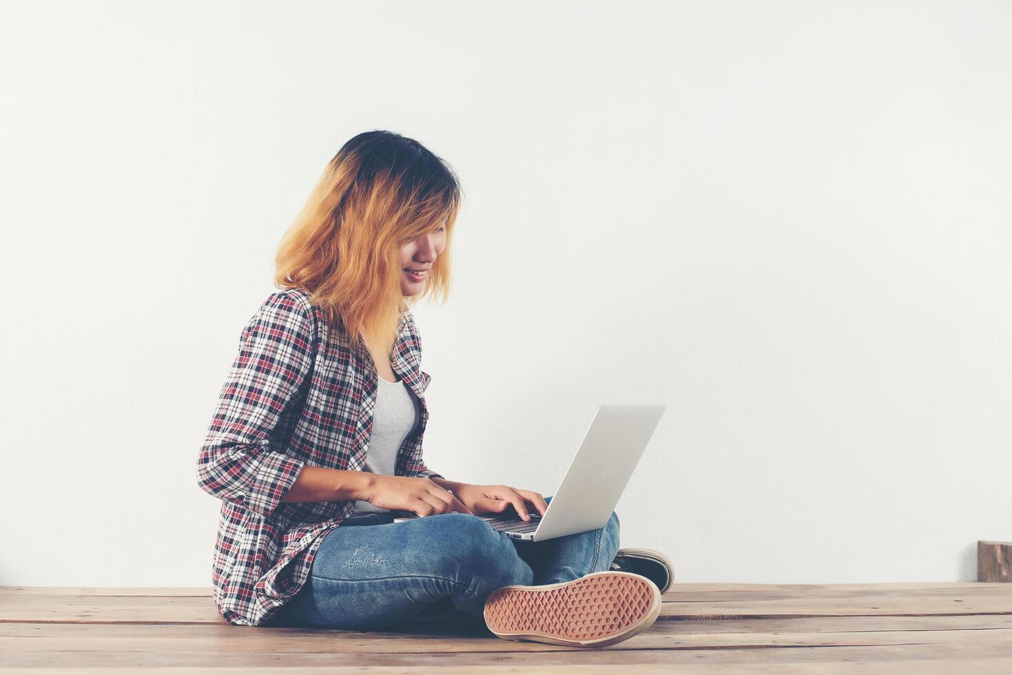 Young hipster woman sitting on wooden floor with crossed legs. photo